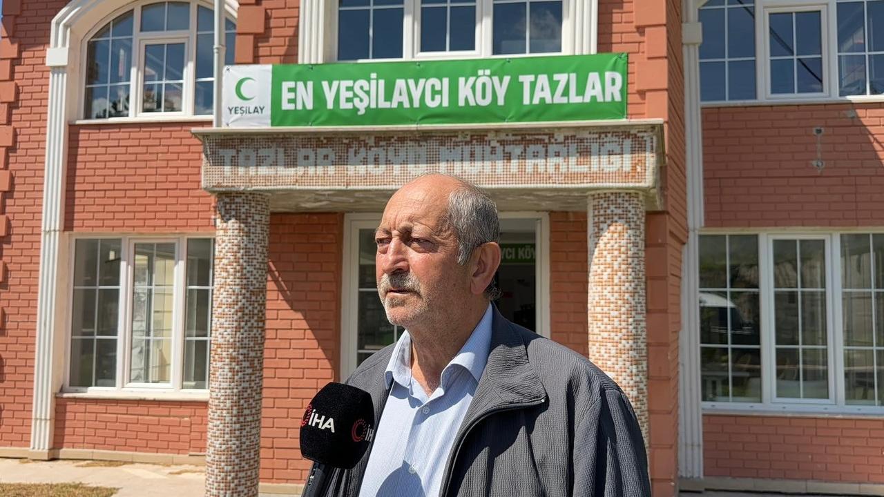 Mehmet Aydogmus, head of the Tazlar Village Development Association, speaks in front of a building marked with a sign calling Tazlar the "most Yesilay-minded village" in Afyonkarahisar, western Türkiye, June 15, 2026. (IHA Photo)