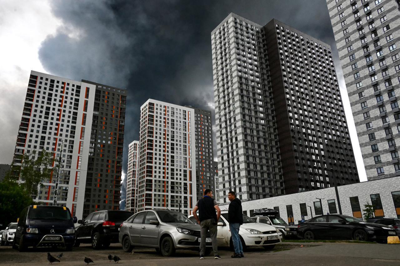 Men interact in a residential locality blanketed in black smoke in Moscow on June 18, 2026. (AFP Photo)