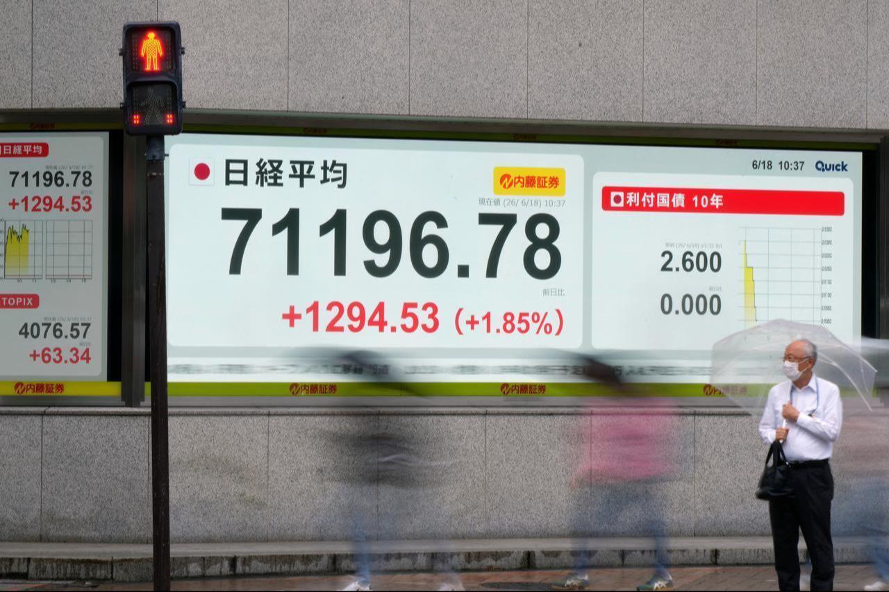 Pedestrians walk past an electronic quotation board displaying the Nikkei Stock Average on the Tokyo Stock Exchange in Tokyo, June 18, 2026. (AFP Photo)