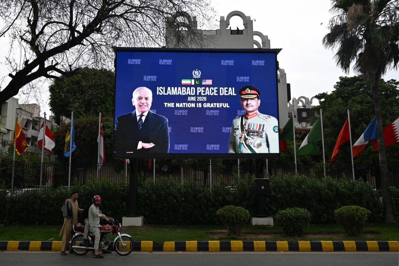 Commuters ride past an electronic board featuring Pakistan's PM Shehbaz Sharif (L) with Army Chief and Field Marshal Syed Asim Munir, displayed in front of the Serena Hotel in Islamabad, June 17, 2026. (AFP Photo)