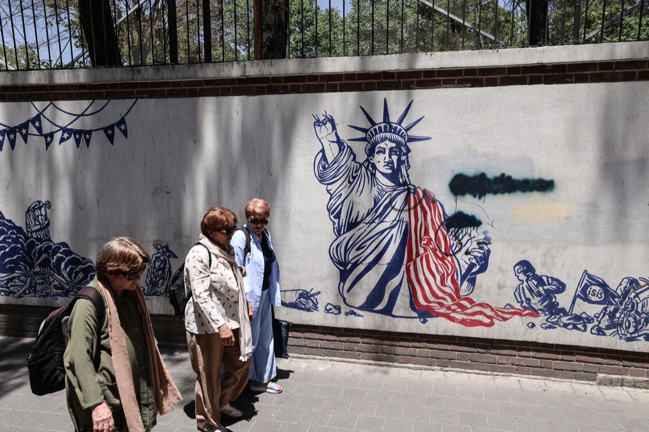 Iranian women walk past anti-US murals outside the former US embassy in Tehran on June 15, 2026. (AFP Photo)