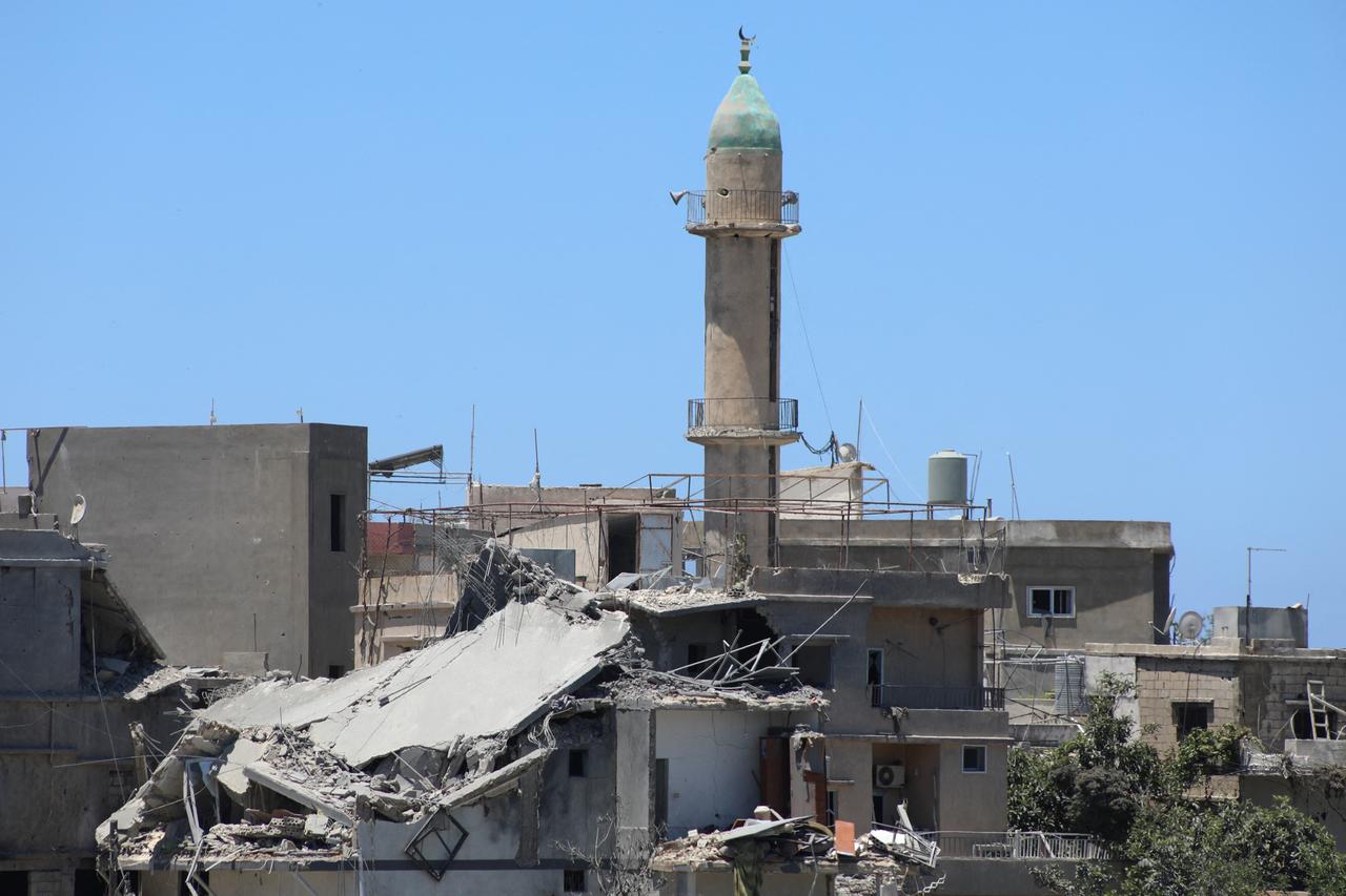 The minaret of a mosque stands behind a heavily damaged building at the site of an Israeli attack that destroyed houses and carpentry shops in the village of Al-Qlailah in the Tyre district in southern Lebanon on June 19, 2026. (AFP Photo)