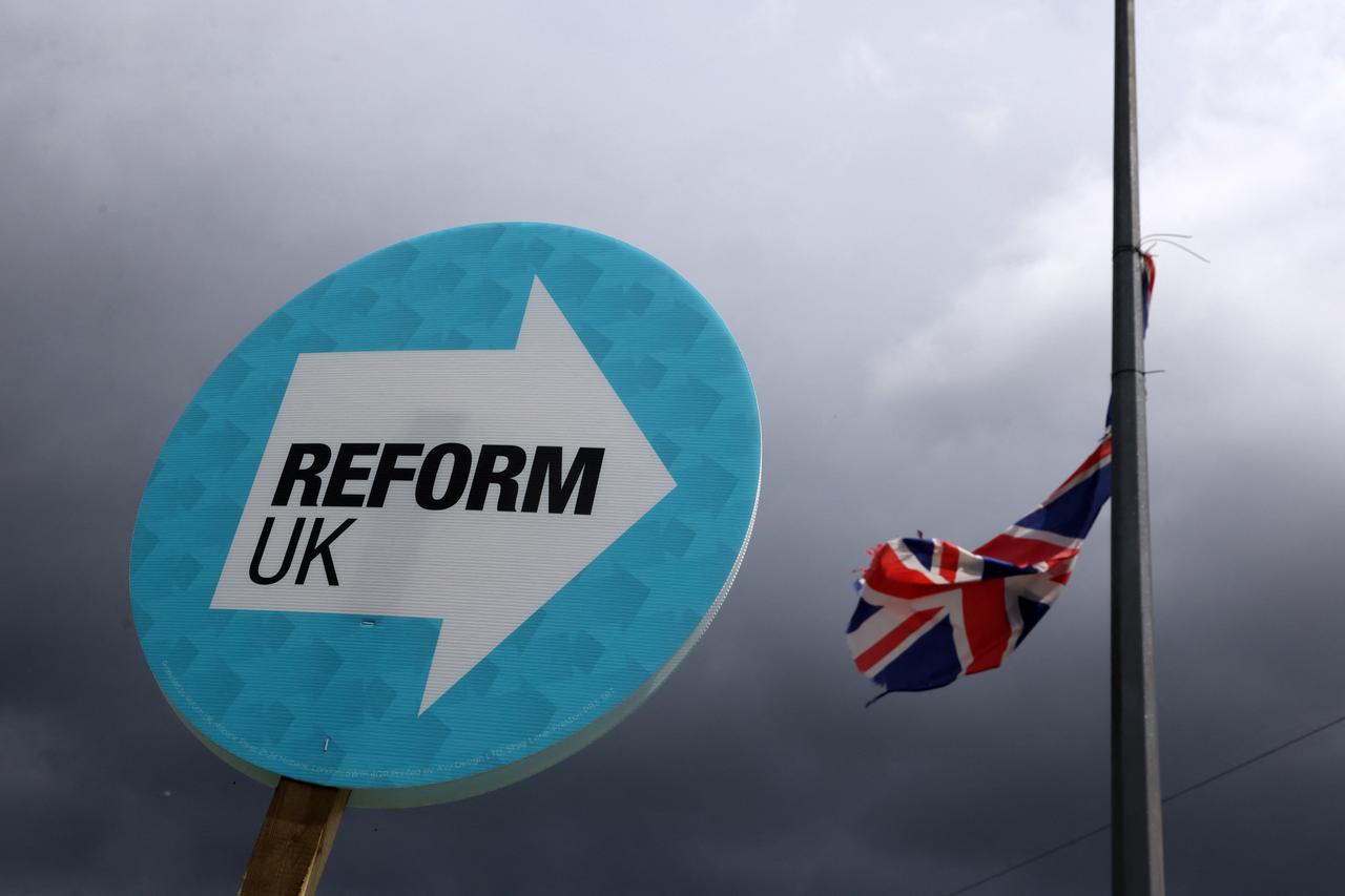A person holds a placard in support of the Reform UK party in the middle of a junction in Bamfurlong, part of the Makerfield parliamentary constituency, in northwest England on June 18, 2026. (AFP Photo)
