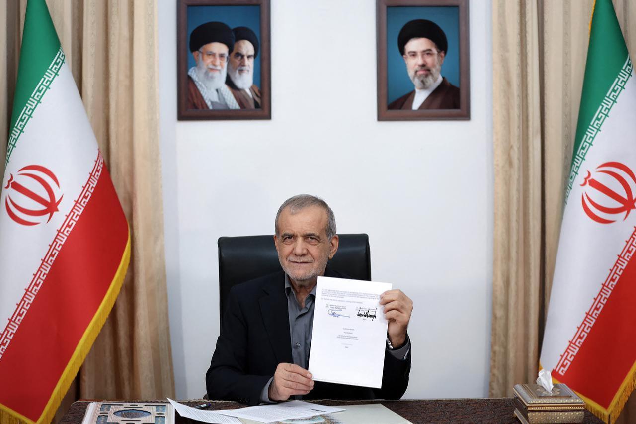 Iran's President Masoud Pezeshkian holds a Memorandum of Understanding document showing his signature and that of US President Donald Trump, in Tehran, June 18, 2026. (Photo by Iranian Presidency/AFP)