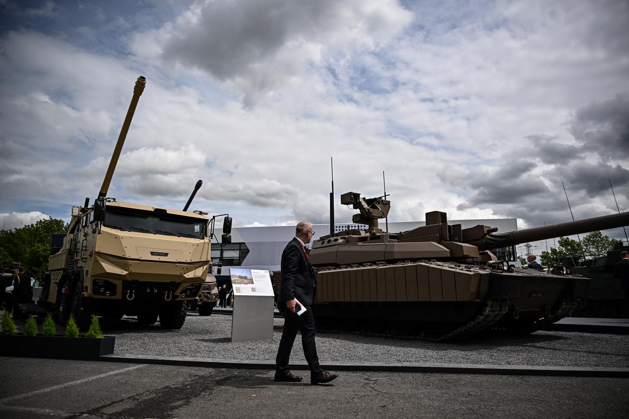 A visitor walks past a military truck equipped with a Cesar canon and a Nexter Systems Leclerc tank at the Eurosatory international land, air defence and security trade fair, in Villepinte, a northern suburb of Paris, France, June 17, 2024. (AFP Photo)
