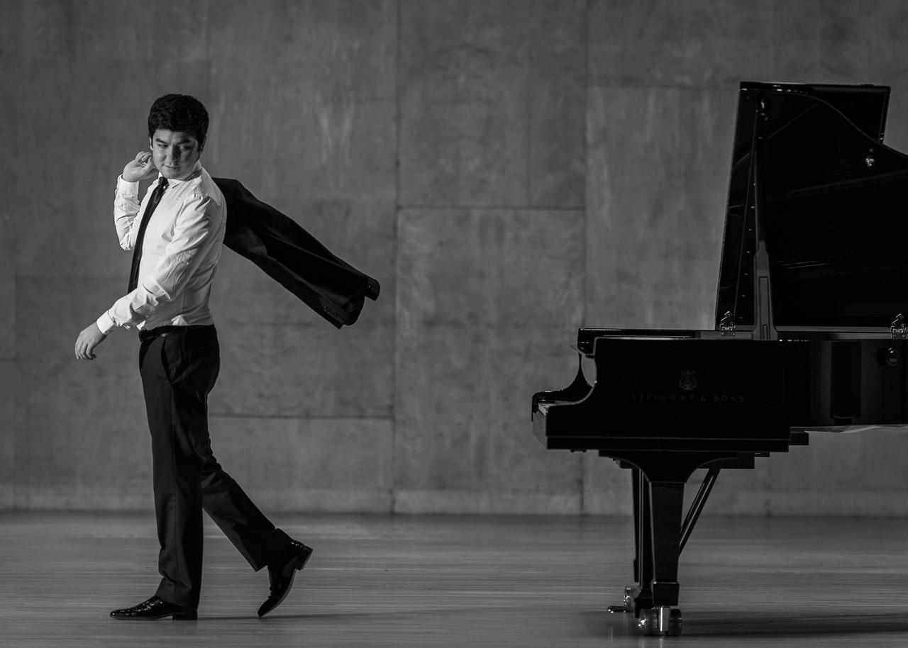 Behzod Abduraimov, who will join the Tekfen Philharmonic Orchestra for the festival’s opening concert, poses beside a grand piano. (Photo via IKSV)