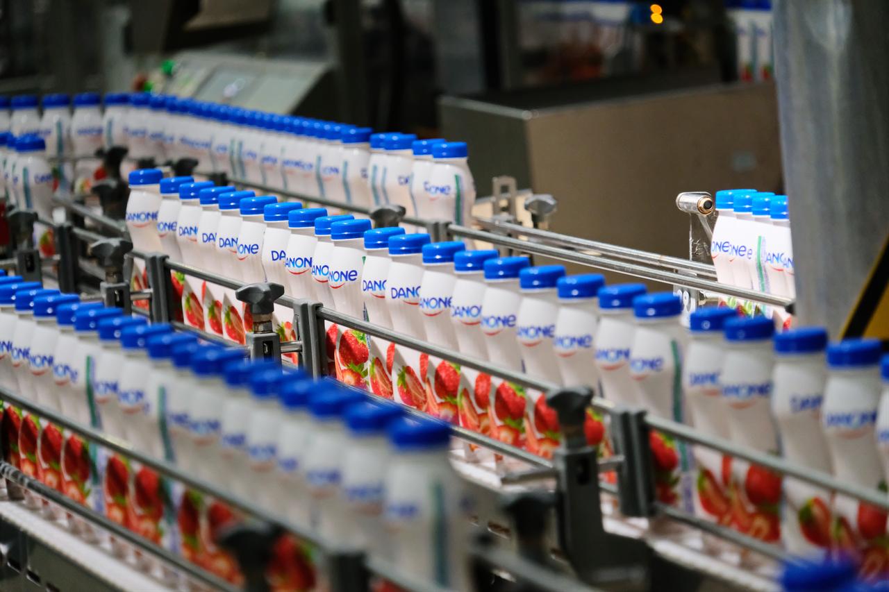 Conveyor belt with Danone yogurt bottles in factory. (Photo via Adobe Stock)