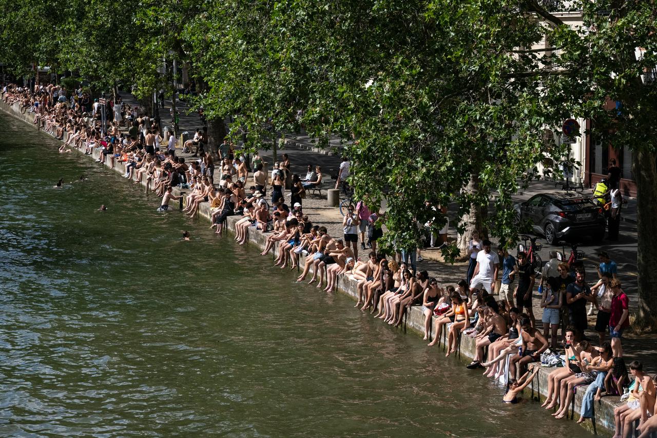 Swimmers sunbath on the banks of the Canal Saint-Martin as France experiences a heatwave in Paris, on June 20, 2026. (AFP Photo)