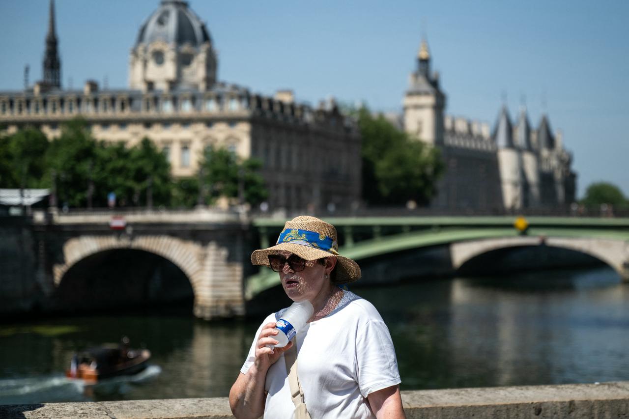 A woman with a hat cools off with a cold bottle of water on the Seine riverside in Paris, France, on June 21, 2026. (AFP Photo)
