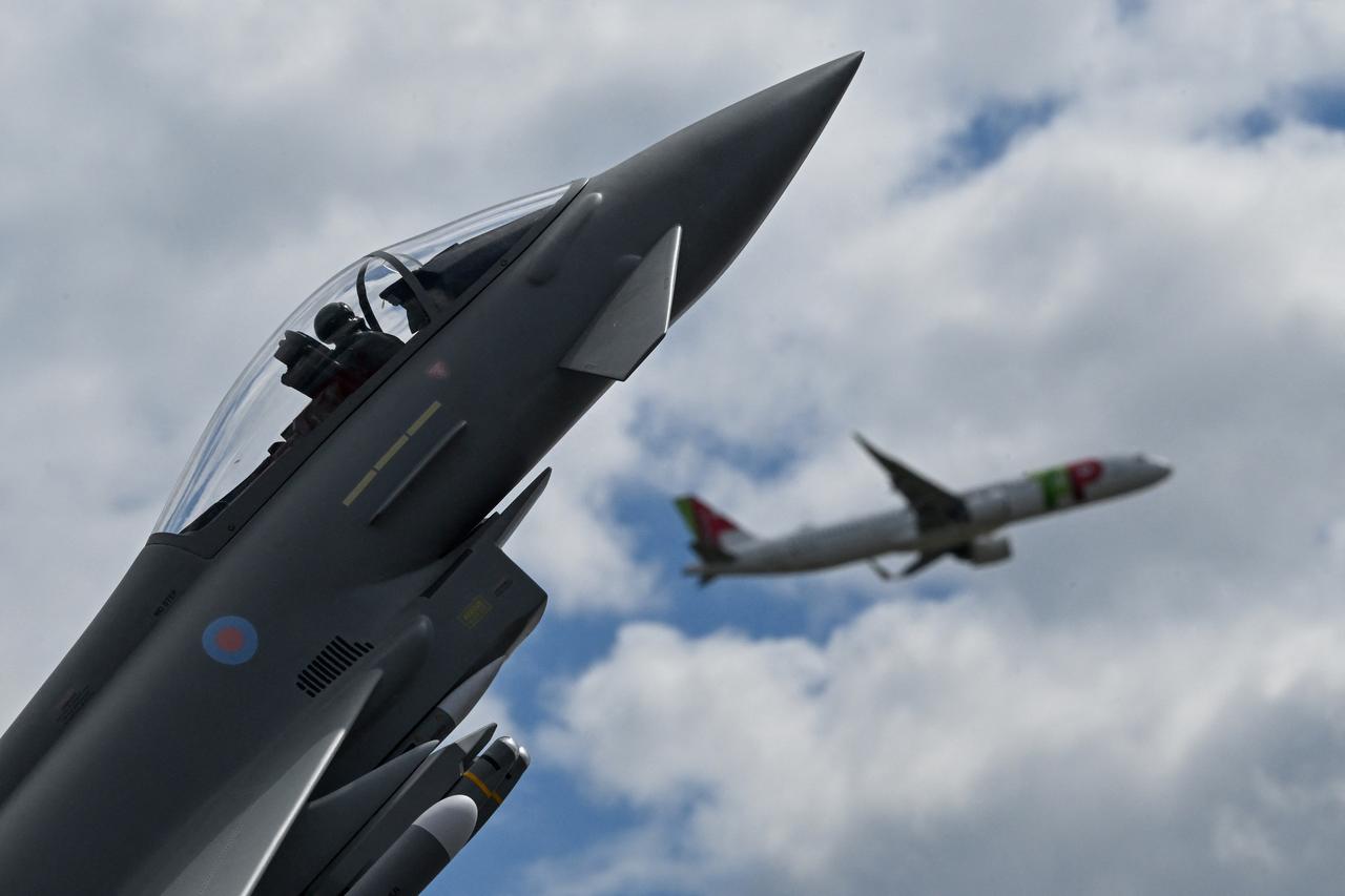 A model of the Eurofighter combat aircraft is on display as a passenger jet of TAP Air Portugal takes off at the BER Airport in Schoenefeld, southeast of Berlin, on June 11, 2026. (AFP Photo)