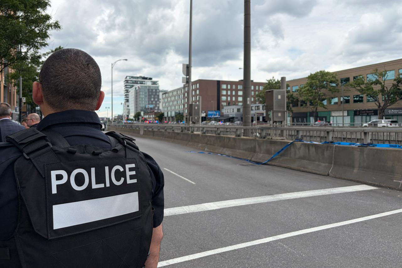 A police officer looks toward the scene of a shooting (near the tall building at L) in Montreal on June 22, 2026. (AFP Photo)