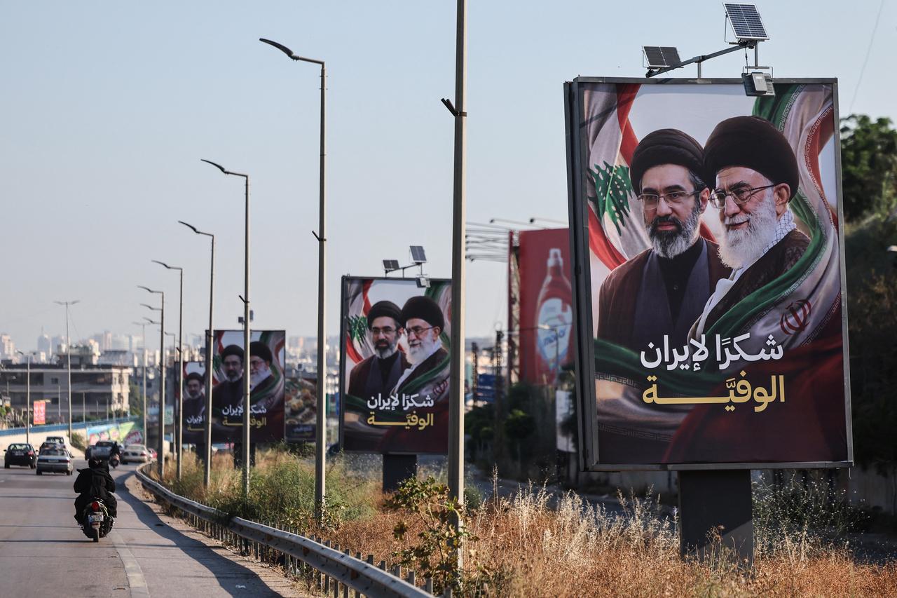 Cars and motorbikes drive past billboards showing Iran’s new Supreme Leader Mojtaba Khamenei (L) and his late father Ali Khamenei (R), with the slogan “Thank you, loyal Iran,” erected along the highway leading to Rafic Hariri International Airport in Beirut on June 22, 2026. (AFP Photo)