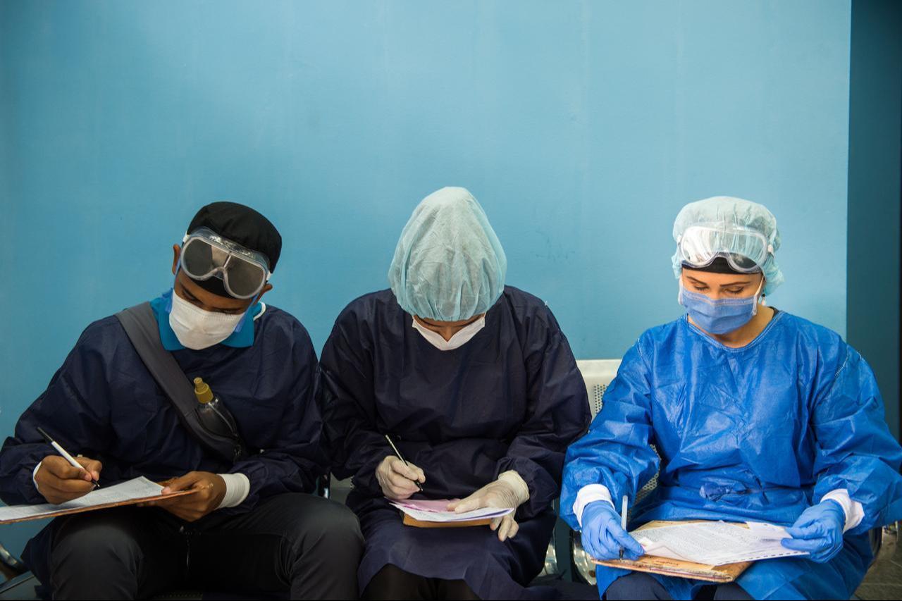Doctors compare notes during a Covid-19 quick test searching after interviewing inhabitants of the Simon Rodriguez Urbanization in Caracas, December 15, 2020. (AFP Photo)