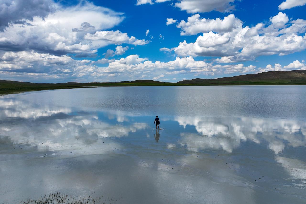 A man takes photos at Akgöl, which refilled after heavy rainfall and drew visitors with its Tuz Gölü-like scenery, in Özalp, Van, Türkiye, June 23, 2026. (AA Photo)