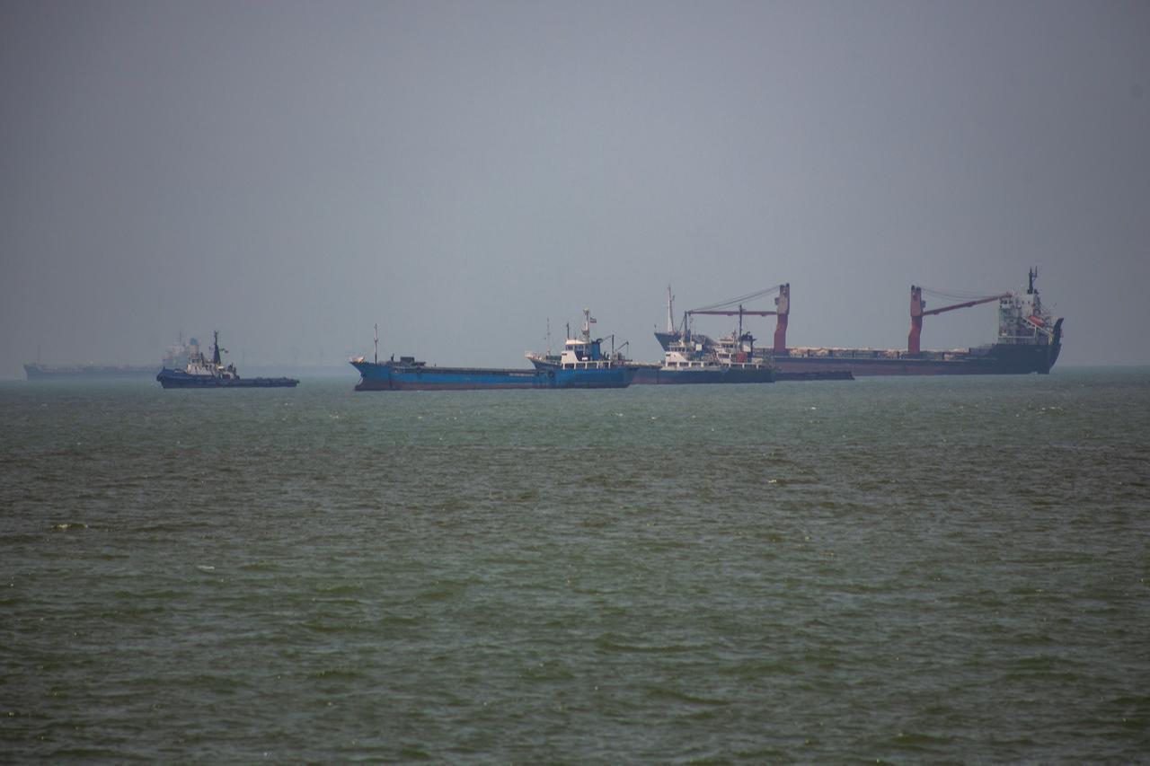 Large commercial vessels and a small boat navigate the waters off the southern port city of Bandar Abbas, Iran, on June 21, 2026. (AA Photo)