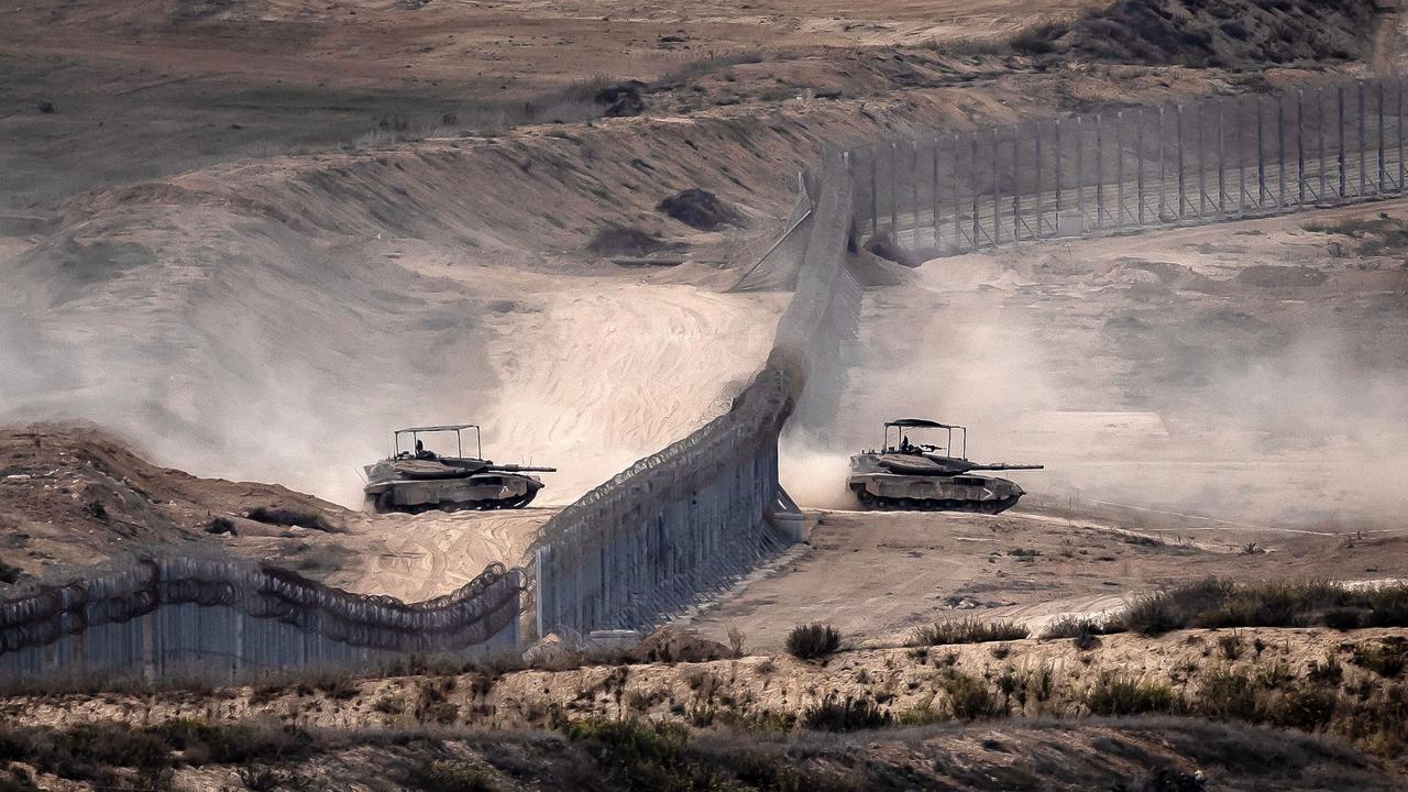 Israeli tanks cross a barbed wire fence at a position along the border with the Gaza Strip and southern Israel on November 12, 2023. (AFP Photo)