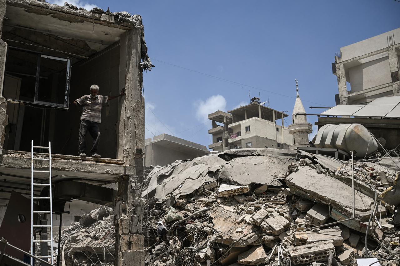 A construction worker rests as he removes debris from a damaged building next to a flattened building at the site of an earlier Israeli military strike on a neighbourhood in the southern Lebanese coastal city of Tyre, June 23, 2026. (AFP Photo)