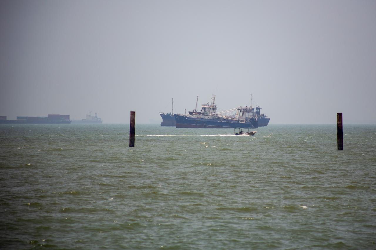 Large commercial vessels and a small boat navigate the waters off the southern port city of Bandar Abbas, Iran, June 21, 2026. (AA Photo)