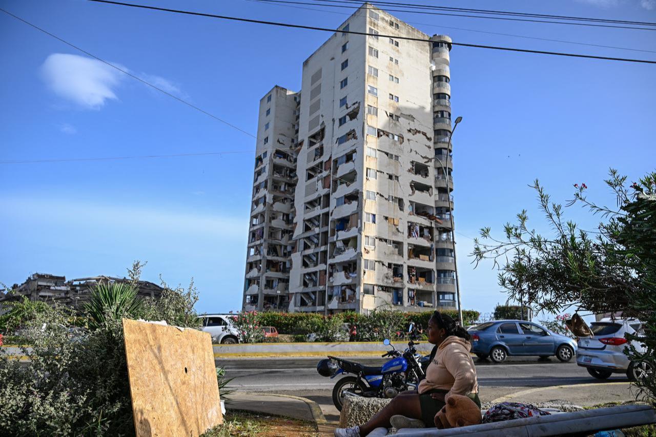 A woman sits before a damaged apartment building following an earthquake in Catia La Mar, La Guaira state, some 30km north-west of Caracas, June 25, 2026. (AFP Photo)