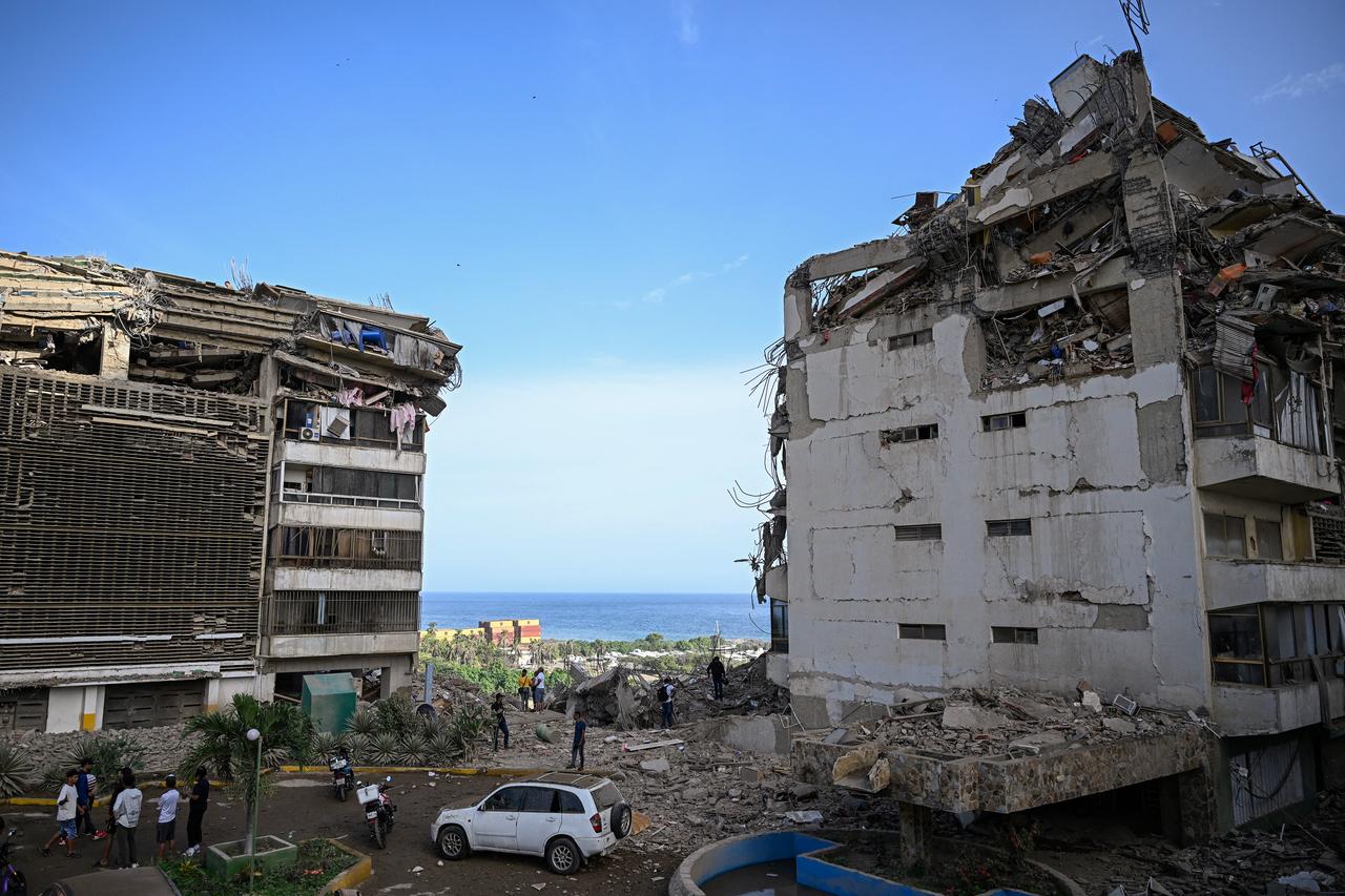 People stand before damaged apartment buildings following an earthquake in Catia La Mar, La Guaira state, some 30km north-west of Caracas, June 25, 2026. (AFP Photo)