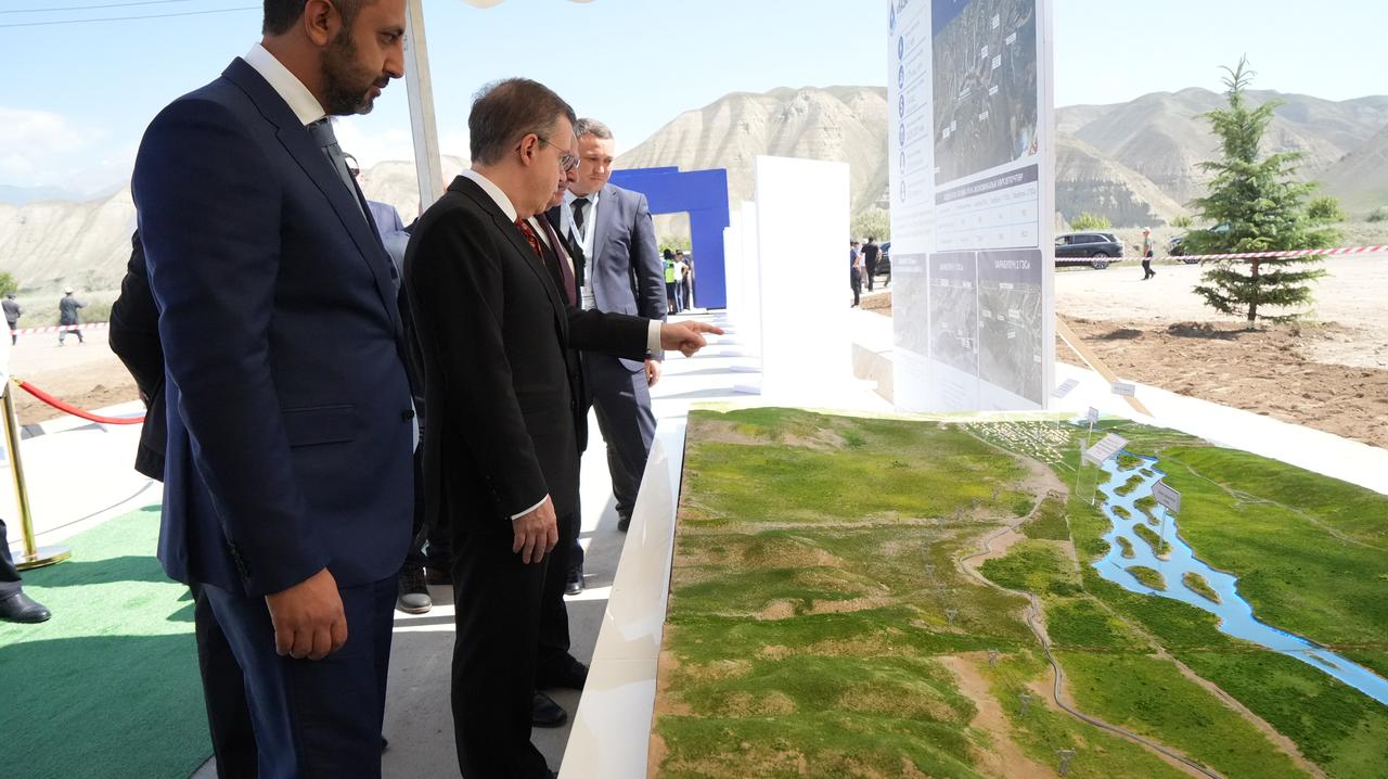 Ihlas Holding Chairman Ahmet Mucahid Oren (center) reviews a site model of the Kazarman Hydropower Plant project during the capsule placement and groundbreaking ceremony in Kyrgyzstan, June 25, 2026. (IHA Photo)