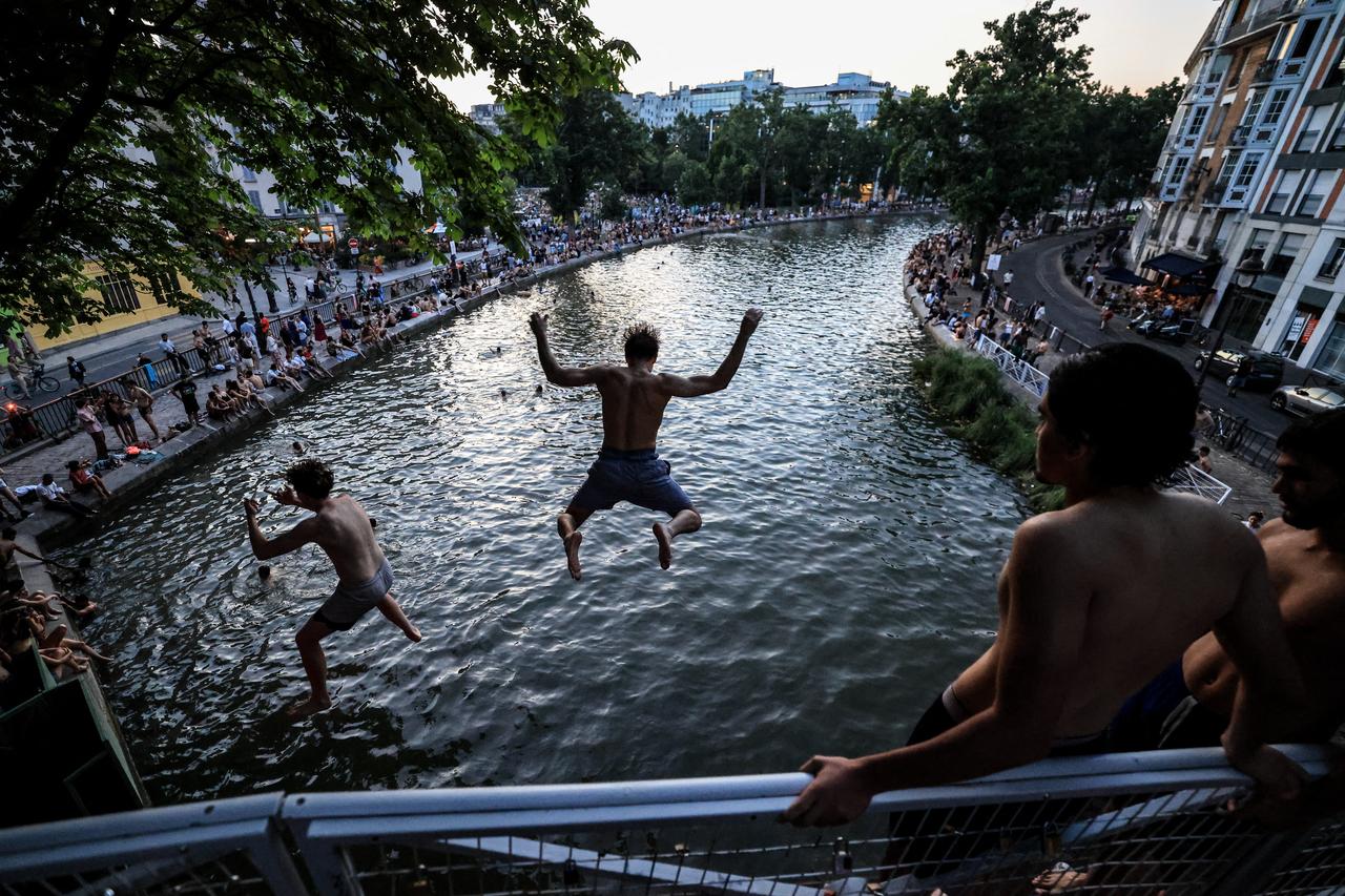 Youths jump from a bridge into the Canal Saint-Martin as France experiences a heatwave, in Paris, June 25, 2026. (AFP Photo)