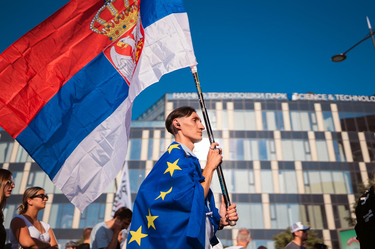 A young Serbian man carries flags of Serbia and EU as large group of students and other citizens of Serbia gather during a protest in Novi Sad, on June 20, 2026. (AFP Photo)