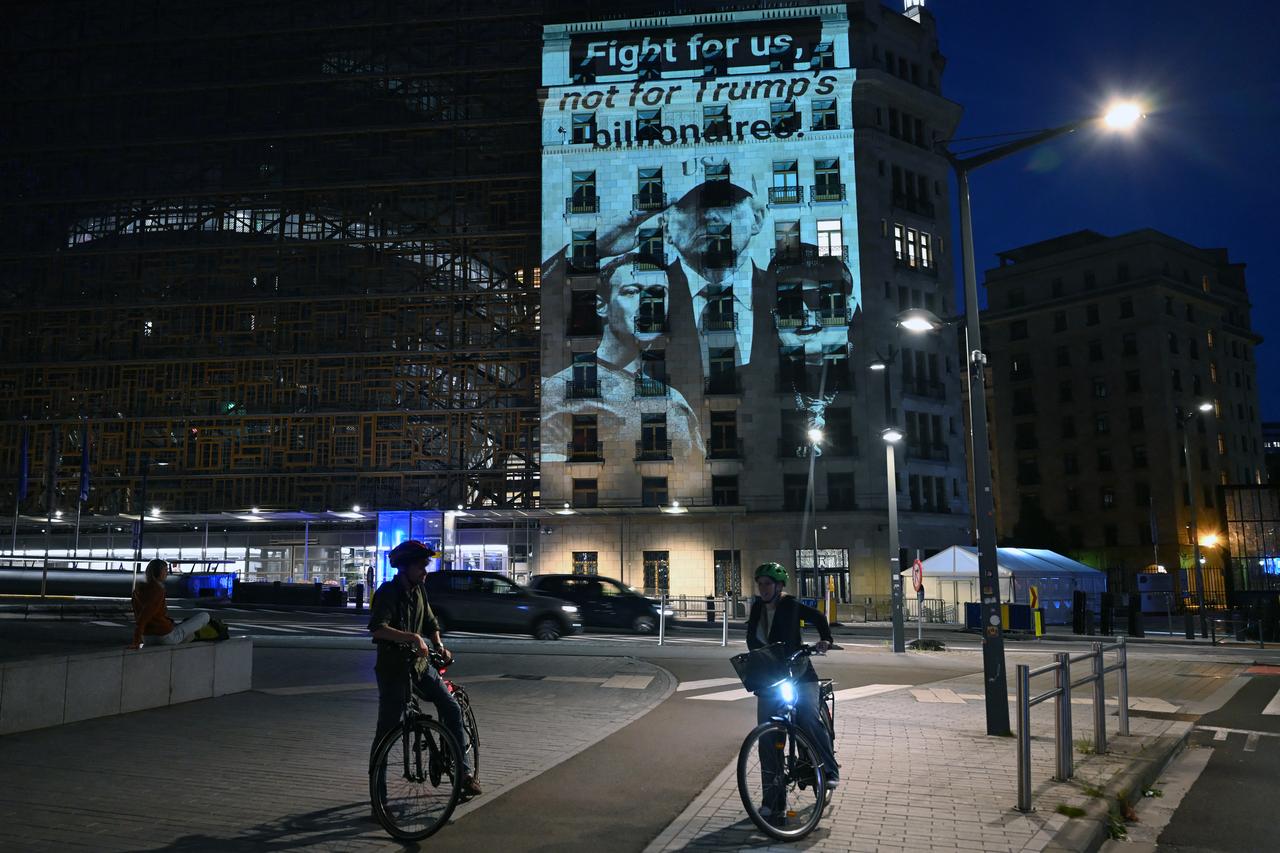 This photograph shows a projection reading "Fight for us, not for Trump's billionaires" with portraits of US President Donald Trump, Meta CEO Mark Zuckerberg, and Tesla CEO Elon Musk, on the facade of the EU Council building, on the eve of a EU Summit, in Brussels on June 17, 2026. (AFP Photo)