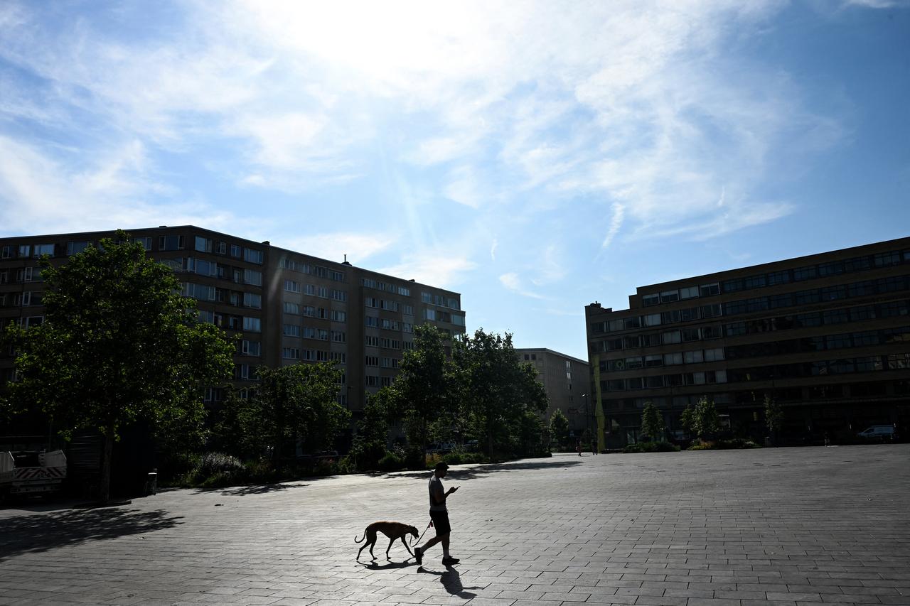 A man walks his dog across the Place Flagey square in Brussels during a heatwave on June 22, 2026. (AFP Photo)
