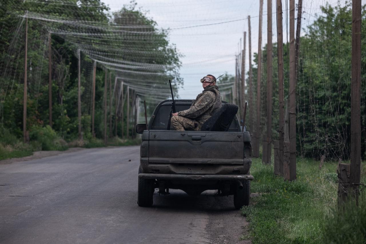 In this handout photograph taken on June 4, 2026 shows a Ukrainian soldier sits in the back of a car parked on the side of a road covered with a net to protect vehicles from drone attacks. (Photo by Iryna Rybakova/The 93rd Kholodnyi Yar Separate Mechanized Brigade/AFP)