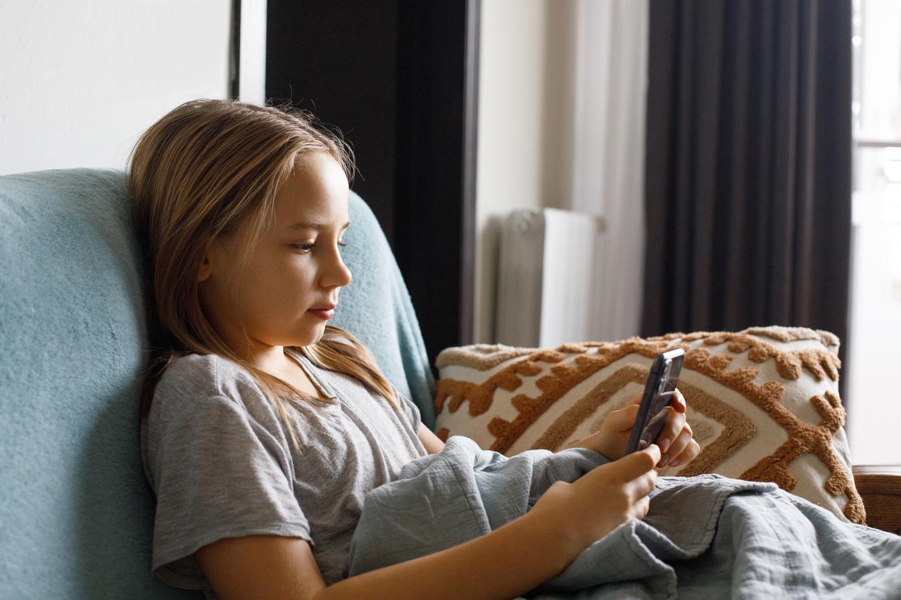 A child uses a smartphone at home. (Adobe Stock Photo)