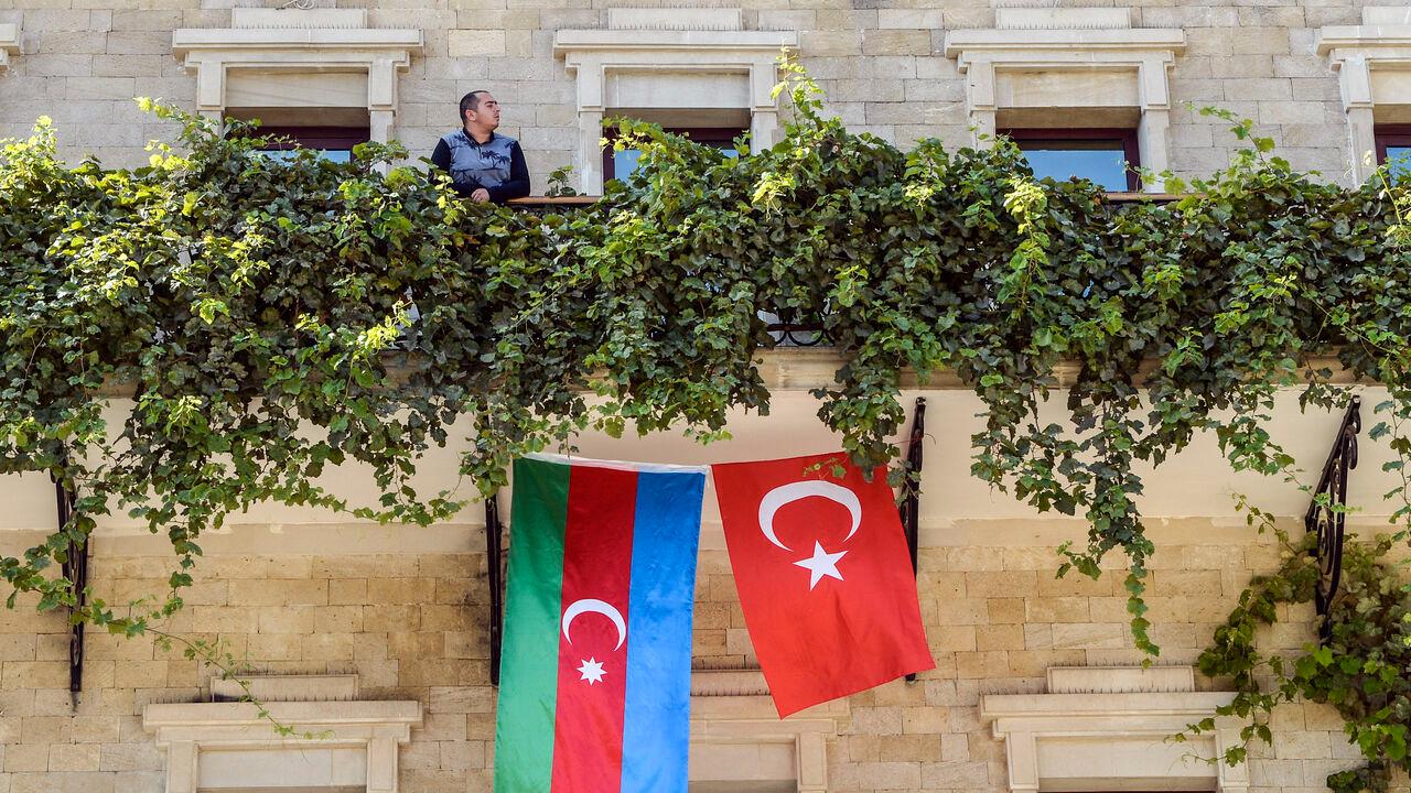 A man stands on the balcony of a hotel with its facade decorated with flags of Azerbaijan and Türkiye in the Old Town of Baku, October 14, 2020. (AFP Photo)
