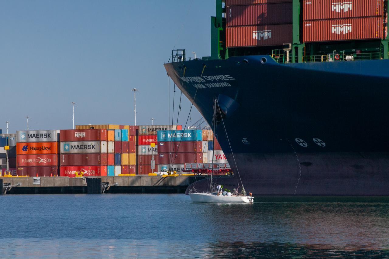 Photo shows cargo ship and sailboat at the Port of Oakland illustrate global trade on the West Coast, accessed on March 28, 2026. (Adobe Stock Photo)