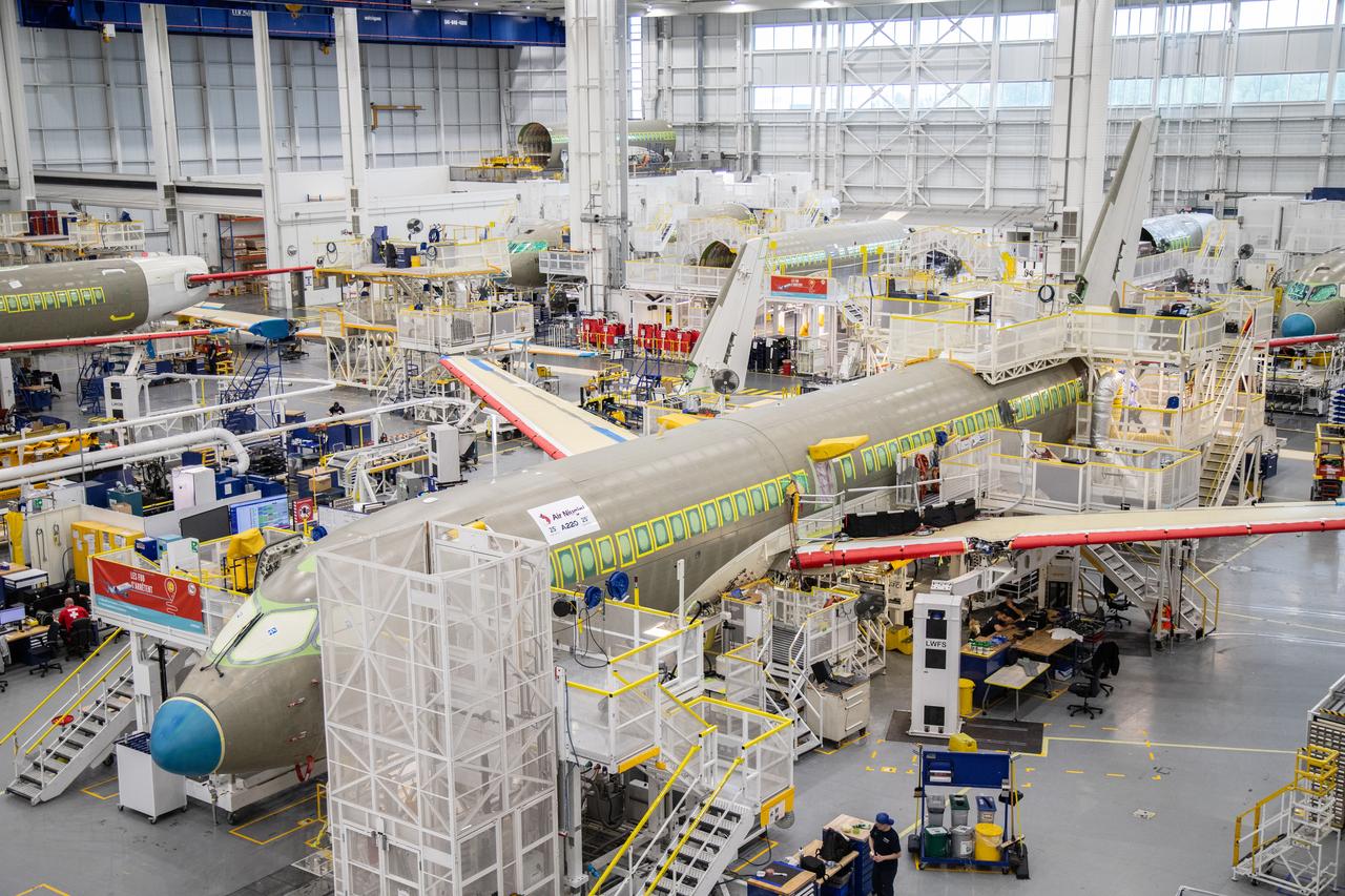 Multiple Airbus aircraft are seen on a final assembly line inside a production facility. (Photo via EIB)