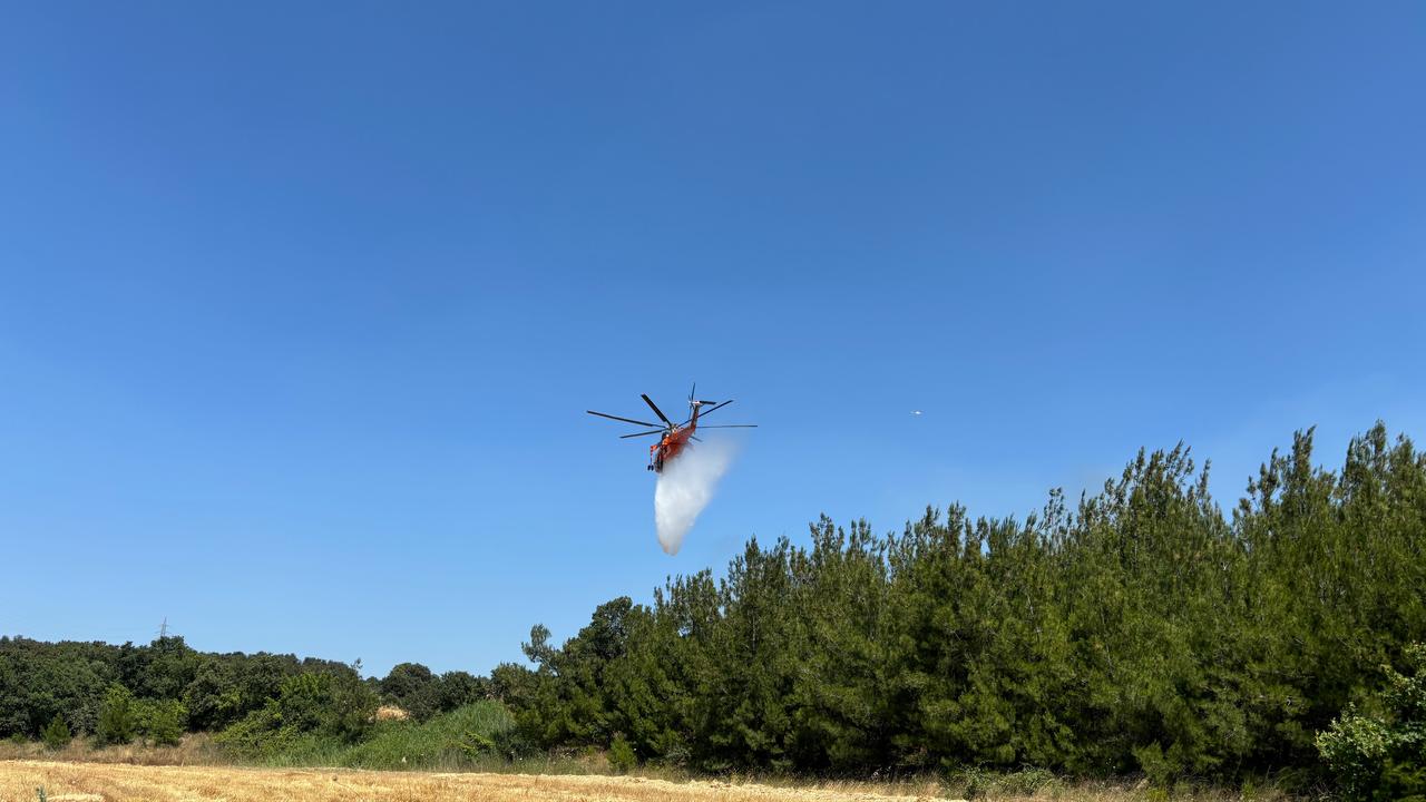 A firefighting helicopter drops water over a forested area during a fire response in Canakkale, northwestern Türkiye, June 29, 2026. (IHA Photo)