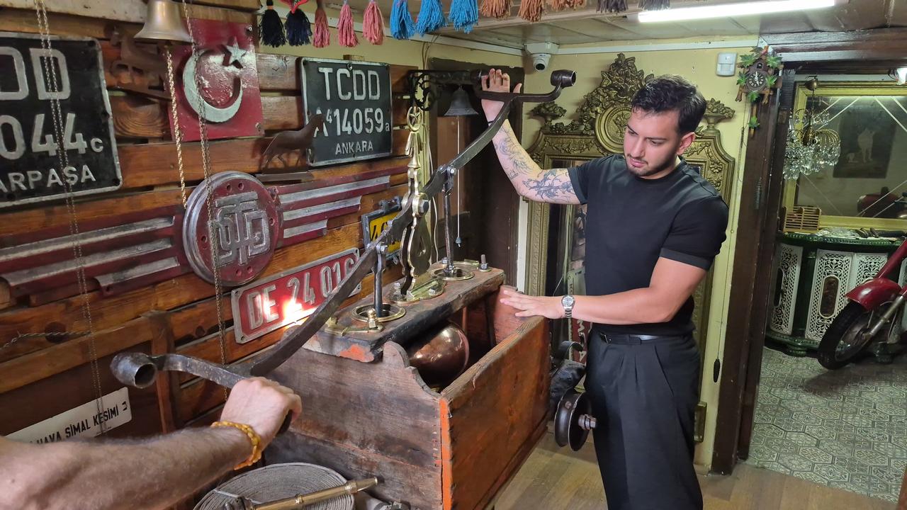 An antique dealer demonstrates the hand-operated mechanism of a historic Ottoman-era tulumba displayed in Eskisehir, Türkiye. (IHA Photo)