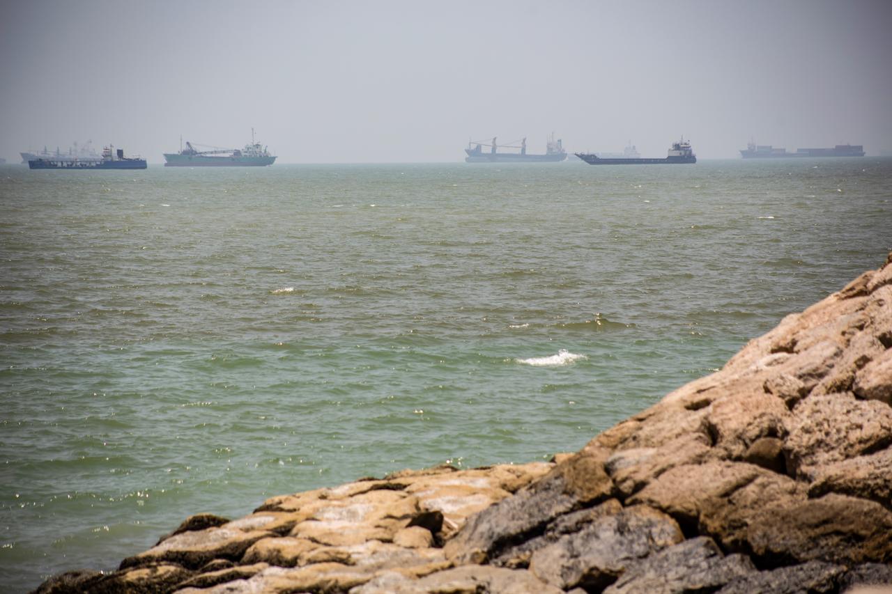 Large commercial vessels and a small boat navigate the waters off the southern port city of Bandar Abbas, Iran, June 21, 2026. (AA Photo)