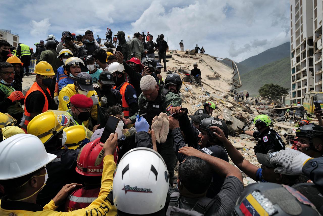 Rescuers carry a person after being pulled alive from the rubble of a collapsed building in Caraballeda, La Guaira state, Venezuela, on June 28, 2026, following earthquakes. (AFP Photo)