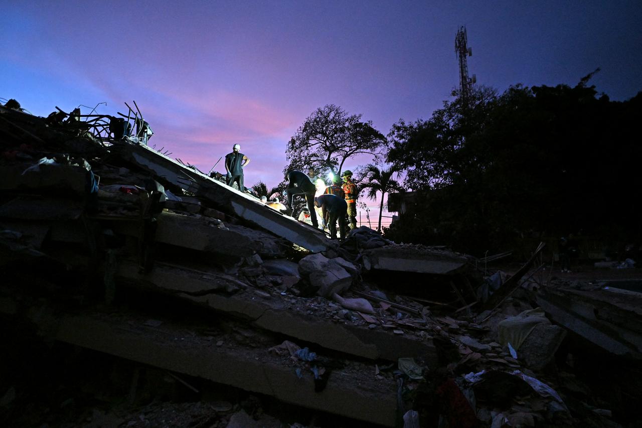 Volunteers and Ecuadorean firefighters of the Urban Search and Rescue (USAR) search for bodies at the site of a collapsed building in Caraballeda, La Guaira State, Venezuela on June 28, 2026, following twin earthquakes. (AFP Photo)