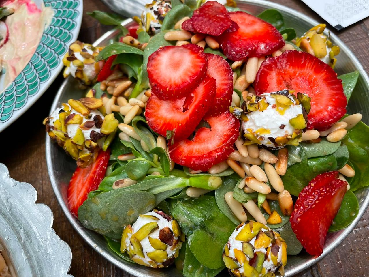 A fresh salad with strawberries, pine nuts and pistachio-coated cheese bites is served as part of the Bursa table in Bursa, Türkiye. (Photo by Koray Erdogan/Türkiye Today)