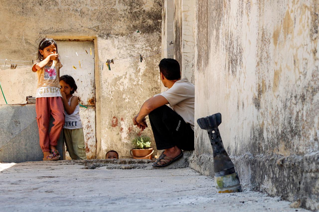 A man speaks with a child while sitting near an unexploded artillery shell that fell during reported overnight Israeli bombardment that hit the village of Abidin in Syria's southwestern Daraa province, close to the Golan Heights, on June 29, 2026. (AFP photo)
