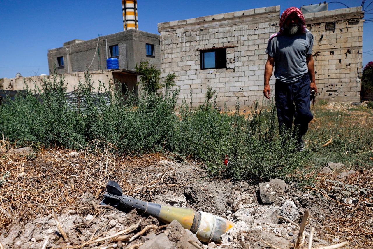 A man stands near an unexploded artillery shell that fell during reported overnight Israeli bombardment that hit the village of Abidin in Syria's southwestern Daraa province, close to the Golan Heights, on June 29, 2026. (AFP photo)
