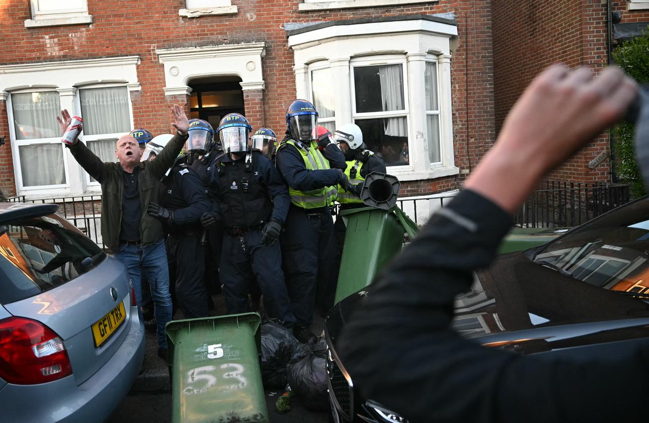 A person attempts to calm the crowd as Police officers are attacked by demonstrators near Portswood Police Station, following a protest march in Southampton, southern England, on June 2, 2026. (AFP Photo)