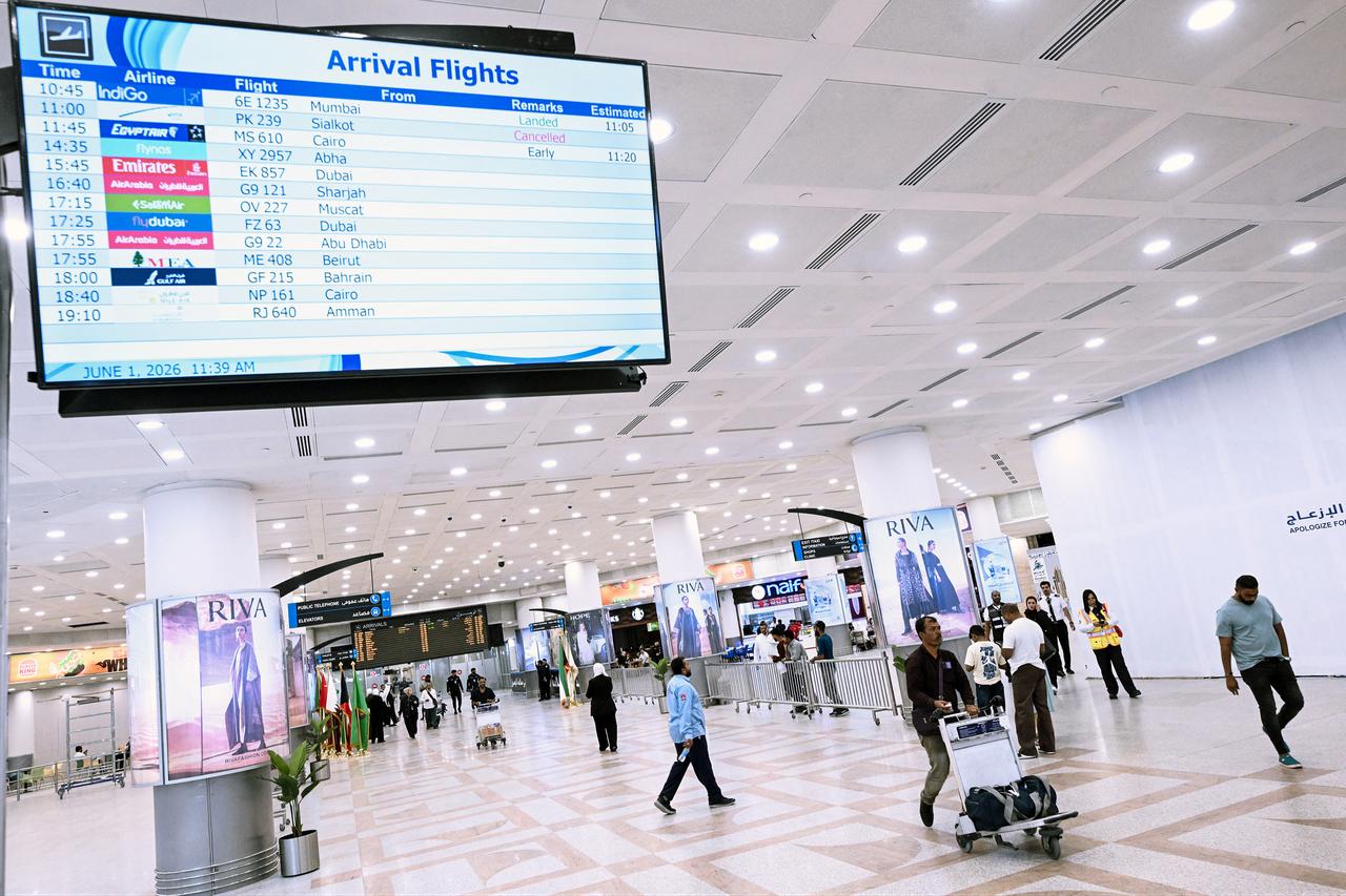 Passengers walk past a screen displaying flight arrival information at Kuwait International Airport in Kuwait City, June 1, 2026. (AFP Photo)