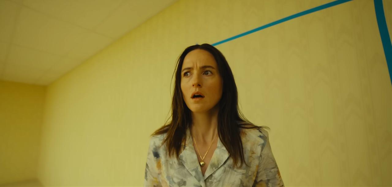 A woman reacts inside a yellow-lit hallway in a screenshot from the “Backrooms” movie trailer. (Photo via YouTube)