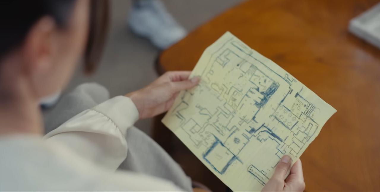 A character studies a hand-drawn map in a screenshot from the “Backrooms” movie trailer. (Photo via YouTube)