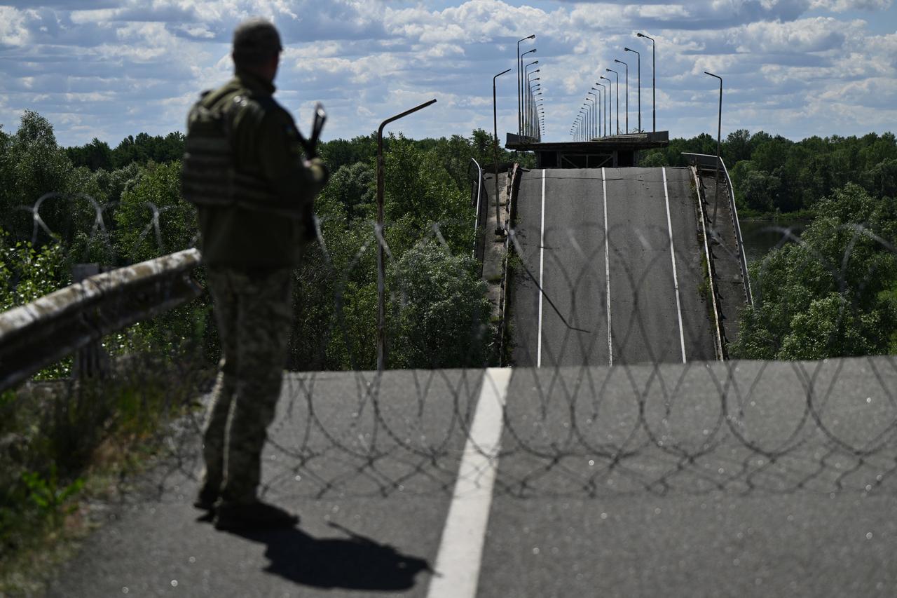 An officer of the State Border Guard Service of Ukraine stands on a destroyed bridge over the Dnipro River, which forms the state border between Ukraine and Belarus in the Chernigiv region, June 1, 2026. (AFP Photo)