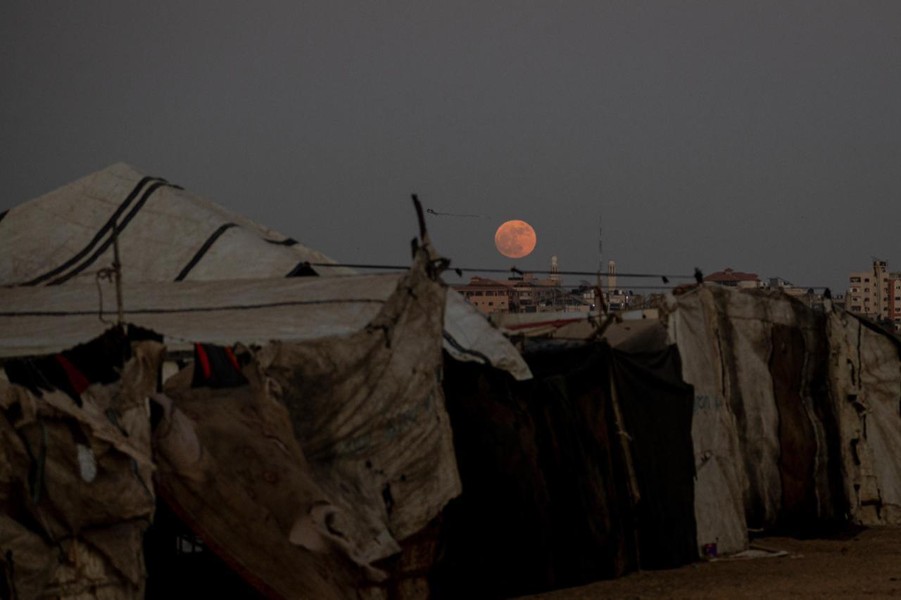 The June full moon, also known as the "Strawberry Moon," appears in the evening sky over the rubble of buildings destroyed by Israeli attacks in Nuseirat, Gaza, Palestine, June 29, 2026. (AA Photo)