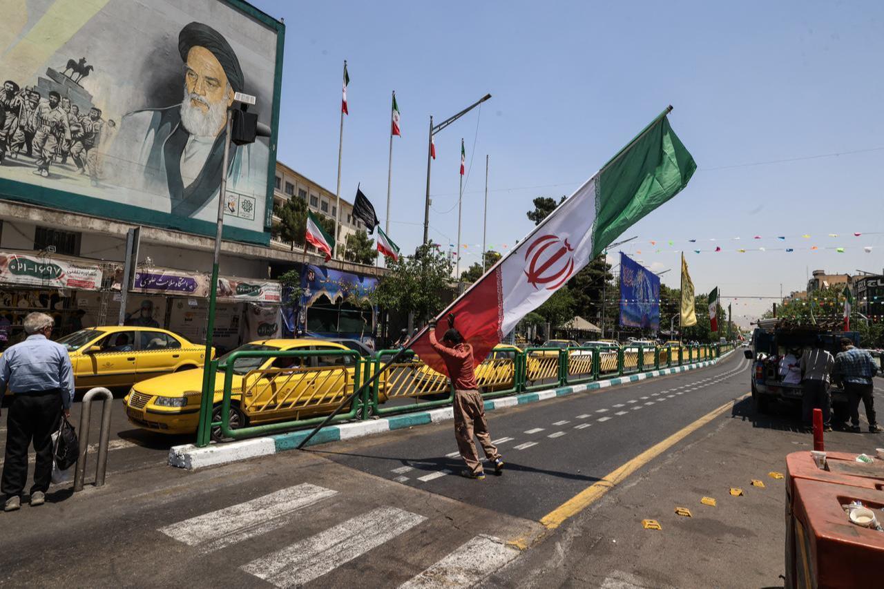 A worker raises a pole bearing the Iranian flag at Enghelab Square in Tehran on June 3, 2026. (AFP Photo)