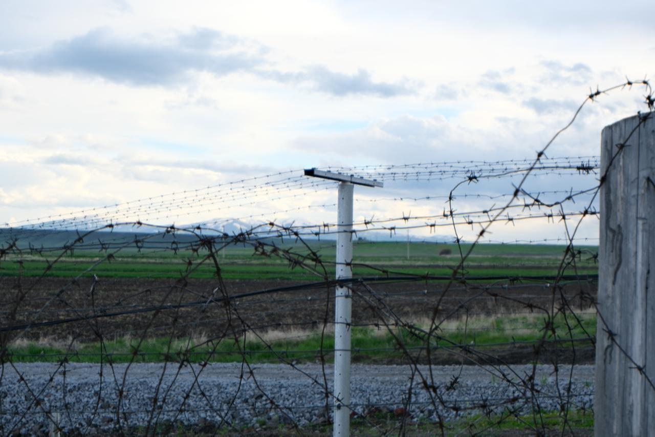 Barbed wire fences line the Akhurik border crossing on the Türkiye-Armenia border, with snow-capped mountains visible in the distance on May 8, 2026. (Yagiz Efe Parmaksiz / Türkiye Today)